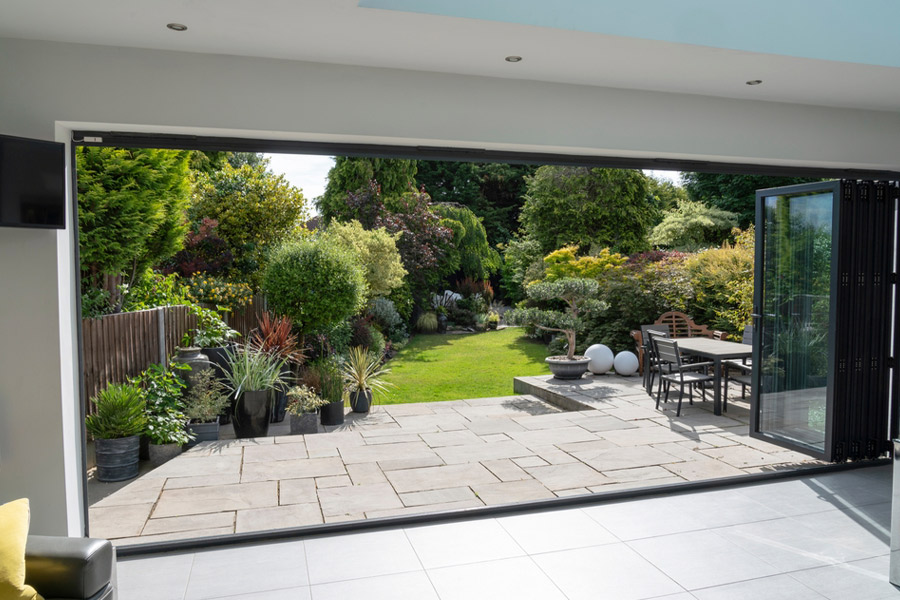 Beautiful-garden-and-patio-in-summer-seen-from-stylish-designer-room-through-bifold-doors.